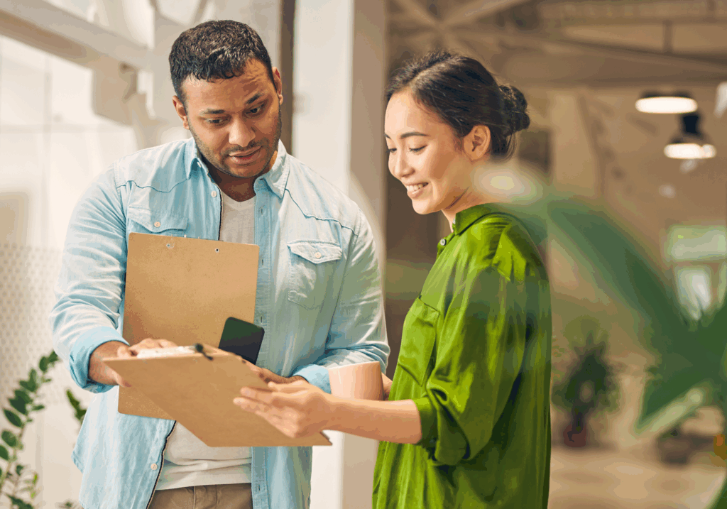 man showing woman a clipboard